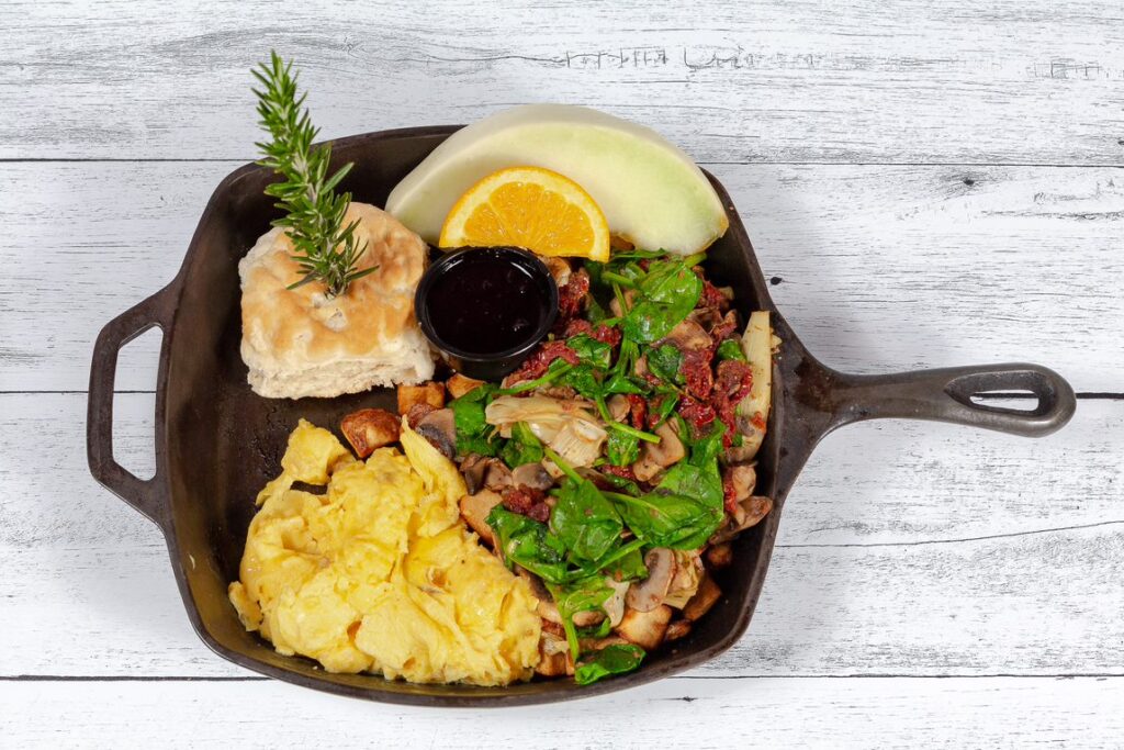 One of the best vegetarian breakfast skillets at Hash House A Go Go at The LINQ, featuring scrambled eggs, spinach, mushrooms, sun-dried tomatoes, and a biscuit.