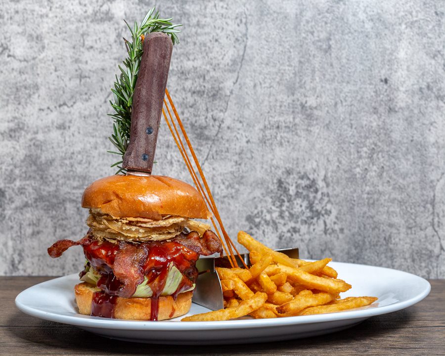 BBQ Bacon Burger with fries at Hash House A Go Go at The LINQ in Las Vegas, topped with crispy onions and a rosemary garnish.