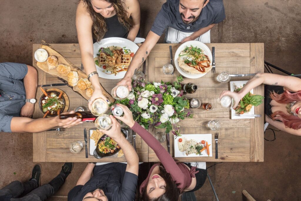 Group toasting during a visit to Hash House A Go Go at The LINQ Las Vegas, with comfort food, cocktails, and signature dishes on the table.