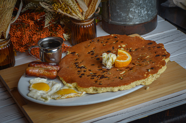 The perfect chocolate chip pancake breakfast at Hash House A Go Go at The LINQ with sunny-side eggs, sausage, and maple syrup.