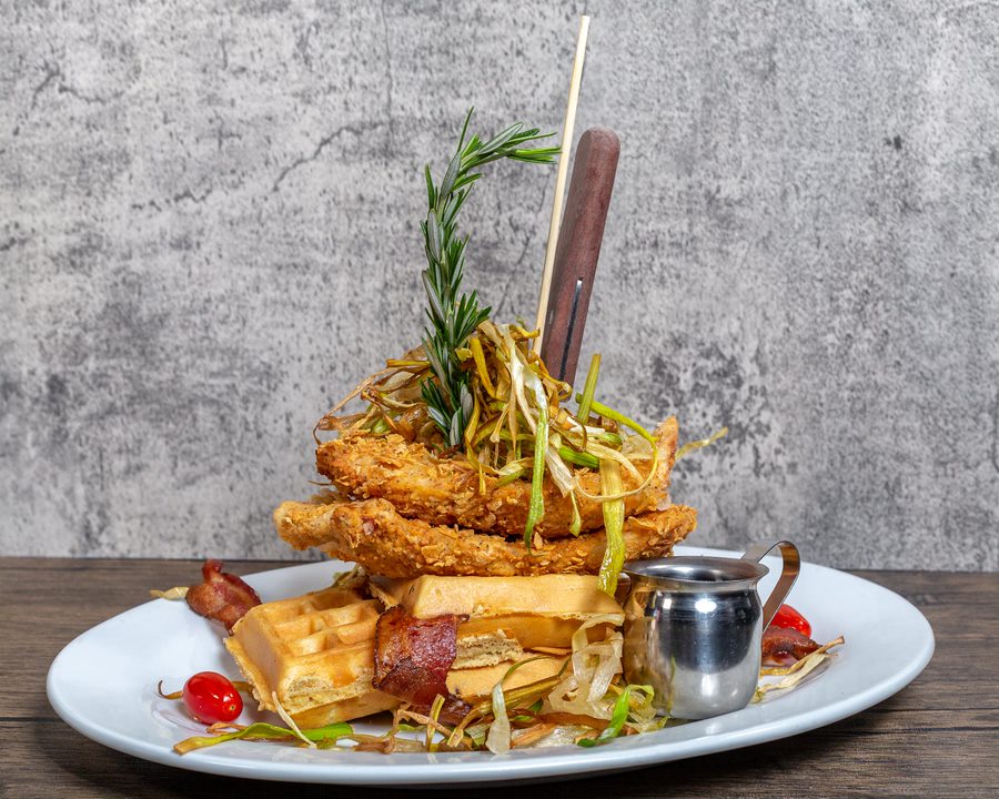 This iconic dish features crispy sage-fried chicken stacked atop bacon-infused waffles, garnished with fried leeks and drizzled with a maple reduction. This is a must visit location! 