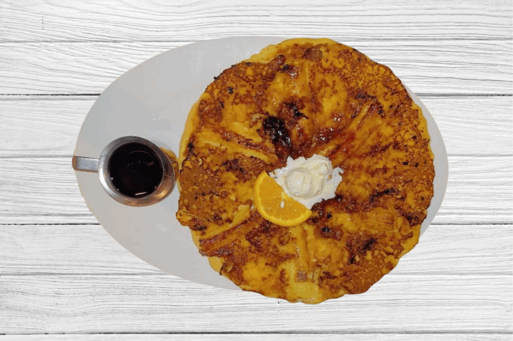 The  Brown Sugar Banana Twisted Flapjack is a cant live without item at Hash House A Go Go The LINQ Las Vegas — oversized pancake topped with butter, orange slice, and syrup
